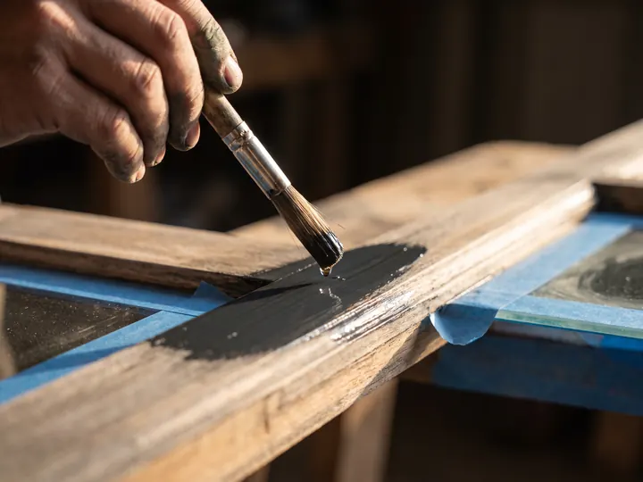 Ein Holzfensterrahmen wird mit dem Pinsel lackiert